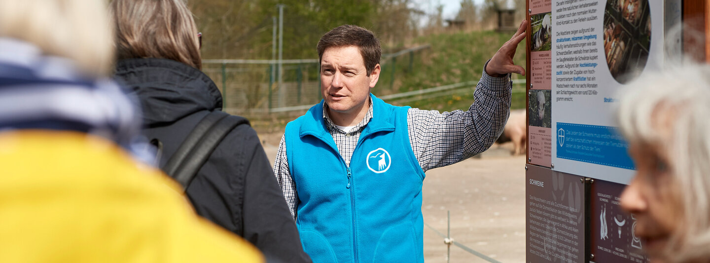 Patrick Boncourt bei einer Führung vor einem Schild im Tierschutzzentrum Weidefeld